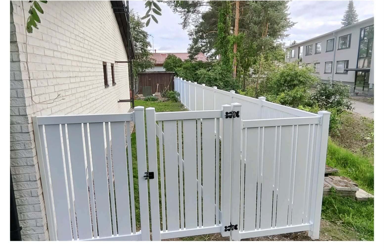 Valkoinen vinyyliaita portaineen talon ja pihan välissä.