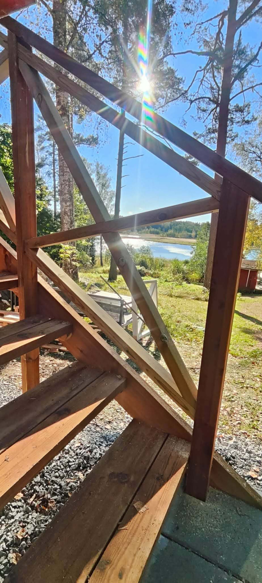 Puiset portaat ja kaide auringonpaisteessa pihalla järvelle.