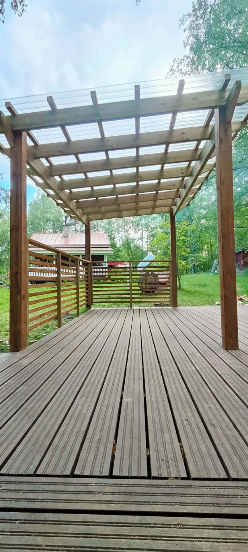 Puinen pergola ja läpikuultava katto terassin päällä.